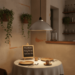 Aluminium pendant light hanging over a dining table set with plates and a chalkboard menu.