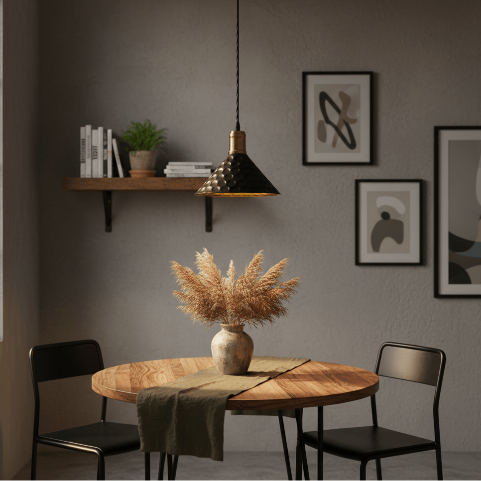 Black iron pendant light hanging above a wooden dining table with a vase of pampas grass.