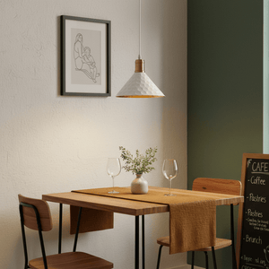 White iron pendant light hanging over a wooden dining table set with glasses and a vase.