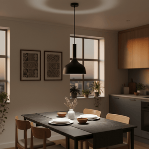 Black metal pendant light hanging above a dining table set with plates and bowls, surrounded by plants.
