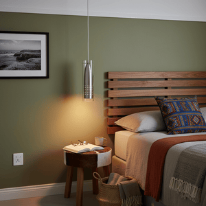 Cord pendant light with clear glass shade hanging above a bedside table with a book and glasses.