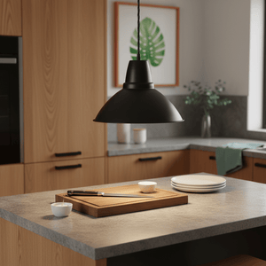 Black aluminium pendant light hanging over a kitchen island with a cutting board and plates.