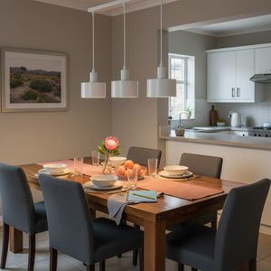 Modern white metal pendant light with three shades above a dining table set for a meal.