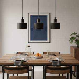 Three black metal pendant lights hang over a wooden dining table set with plates and a fruit bowl.