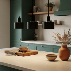 Three black metal pendant lights hang over a kitchen island with wooden and ceramic bowls.
