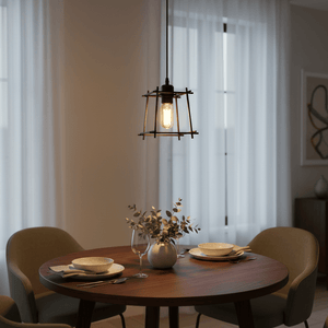Black pendant light hanging over a round dining table set for two, with soft ambient lighting and sheer curtains in the