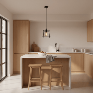 Modern kitchen with a black pendant light hanging above a white marble island, flanked by wooden stools and cabinetry.