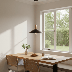 Dining area with a metal and wood pendant light above a wooden table, featuring chairs, a book, and a vase with greenery.
