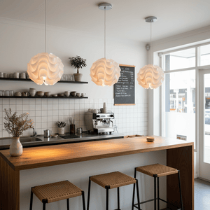 Three white wavy pendant lights hanging above a wooden bar counter in a modern kitchen.
