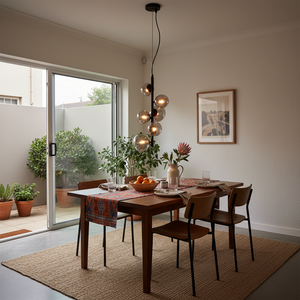 Nebula Metal Pendant with smoke glass shades hanging over a wooden dining table set with fruit and glassware.