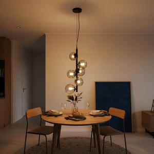 Nebula Metal Pendant with smoke glass shades hanging above a wooden dining table set for two.