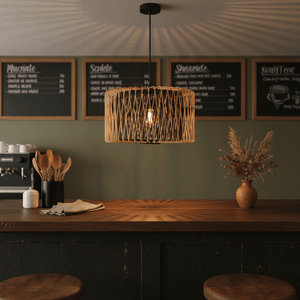 Bamboo and metal pendant light hanging over a wooden bar, casting warm light and shadows.