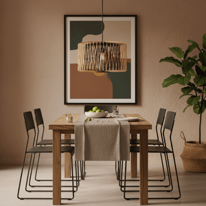 Bamboo and metal pendant light hanging above a wooden dining table set with a bowl of fruit and a neutral table runner.
