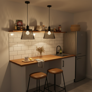 Two black steel-mesh pendant lights hang above a wooden kitchen counter with a sink and decorative items.