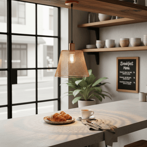 Rose gold mesh pendant light hanging over a breakfast table with croissants and coffee.