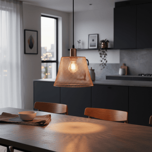 Steel mesh pendant light in rose gold hanging over a dining table, casting warm light and shadows.
