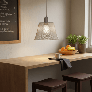 Polished chrome pendant light with white cord hanging over a wooden counter, featuring plants and a bowl of fruit.