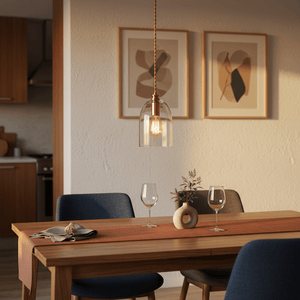 Stylish pendant light with clear glass shade and bronze fitting hanging over a dining table with decor.