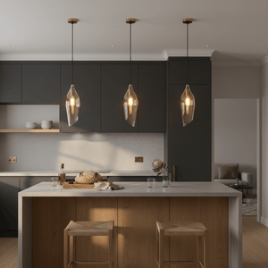 Three satin brass pendant lights with cognac glass shades hang above a modern kitchen island, creating a warm ambiance.