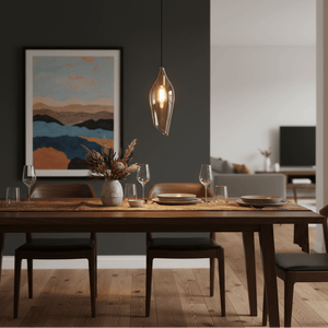 Satin brass pendant light with cognac glass shade hanging above a dining table set with plates and glasses.