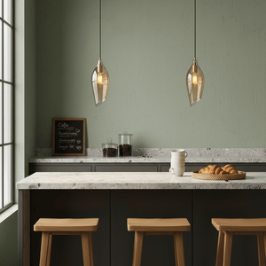 Satin brass pendant light with cognac glass shade hanging over a kitchen island with wooden stools.
