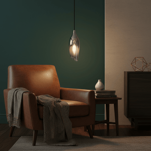 Satin nickel pendant light with smoke glass shade hanging above a cozy brown armchair with a throw blanket.
