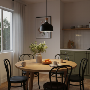 Black metal and wood pendant light hanging above a round wooden dining table with chairs, featuring a vase and fruit bowl.