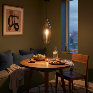 Black metal pendant light with cognac glass shade hanging above a wooden dining table set with food.