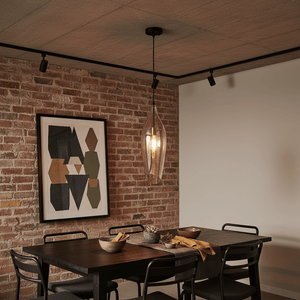 Black metal pendant light with cognac glass shade hanging over a dining table in a modern setting.