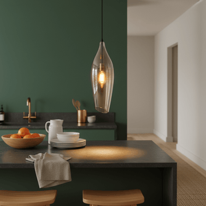 Stylish black metal pendant light with cognac glass shade hanging over a kitchen island with fruit bowl and tableware.