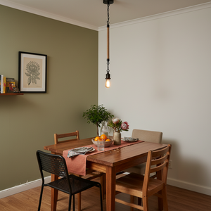 Metal pendant light with rope detail hanging above a wooden dining table set with dishes and flowers.