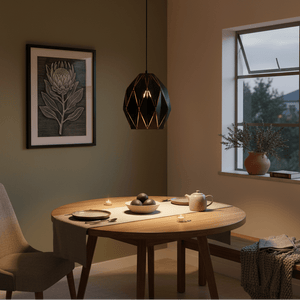 Black metal pendant light hanging above a wooden dining table set with plates and a teapot.
