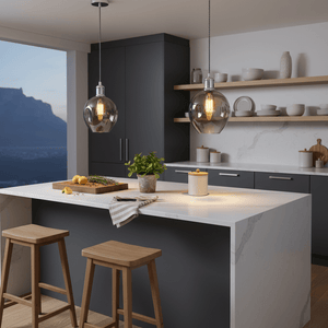 Polished chrome pendant lights with smoke glass shades hanging over a modern kitchen island with wooden stools.