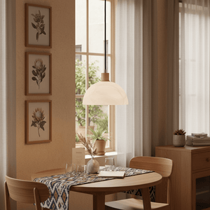Pendant light with alabaster glass and wood finish hanging over a dining table with decor.