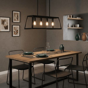 Black 4-light pendant hanging above a wooden dining table set with plates and glassware in a modern interior.