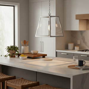 Polished chrome and clear glass pendant light hanging above a kitchen island with wooden accents.