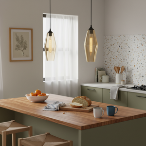 Amber glass pendant lights hang over a wooden kitchen island with fresh fruit and bread.