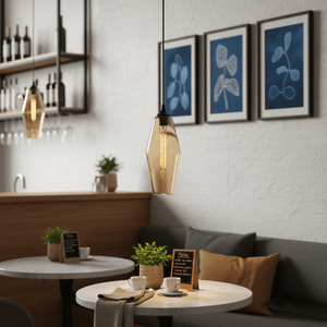 Amber glass pendant light hanging above a cozy café table with plants and coffee cups.