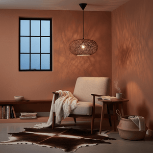 Cozy living space featuring the Twine Pendant light above a chair, casting warm shadows on the wall.