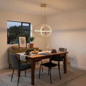 Sleek French Gold LED pendant light hanging above a modern dining table set with dishes and fruit.