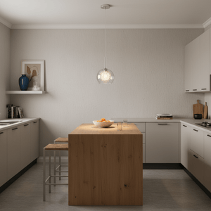 Polished chrome pendant light with clear glass shade hanging above a wooden kitchen island with fruit bowl.