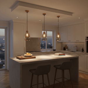 Three gold and amber glass pendant lights hang over a kitchen island, illuminating a countertop with fruit and books.