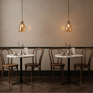 Stylish gold and amber glass pendant lights hanging over a marble table in a cozy café setting.