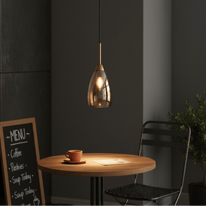Gold and amber glass pendant light illuminating a wooden table with a coffee cup and menu.