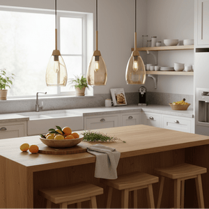 Three gold and amber glass pendant lights hanging above a wooden kitchen island with fresh fruit.