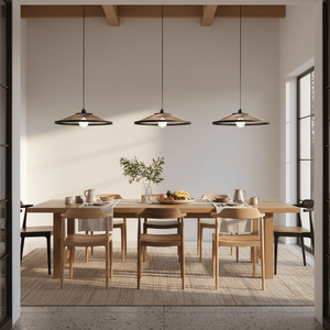 Three Hara Bamboo & Metal Pendant Lights hang over a wooden dining table set with chairs and decor.