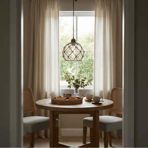 A cozy dining nook featuring the Constantia Rope Pendant Light above a round wooden table set with pastries and drinks.