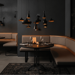 Stylish dining area featuring multiple black pendant lights above a round table with elegant glassware.