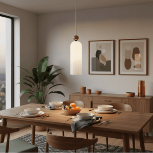 A fluted white-glass pendant light hangs above a wooden dining table set with bowls and fruit, complemented by modern decor.