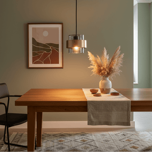 Astrid Gold Pendant Light hanging above a wooden dining table with decorative elements and artwork on the wall.